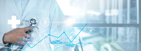 Healthcare business graph data and growth of investment, Doctor hold stethoscope and analyzing medical examination report, Virus pandemic develop attention healthcare and rising growth in hospital.の写真素材