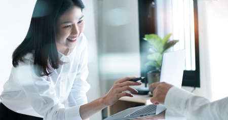 Modern Asian business woman smiling feeling happy seeing growth sale profit on laptop with business partnership at meeting.の写真素材