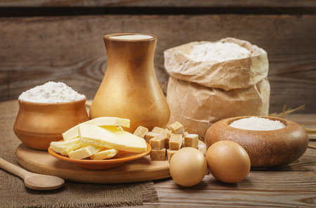 Baking ingredients, flour, butter, milk, sugar and eggs in a rustic style on the old wooden backgroundの写真素材