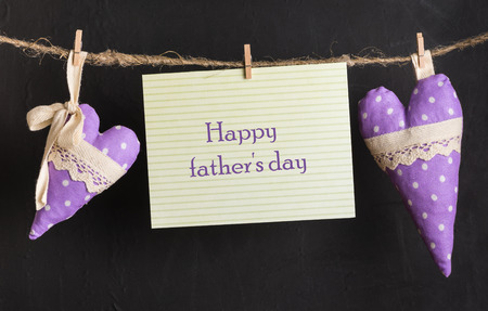 message card with text happy father\'s day and handmade hearts of the cloth with polka dots on a rope with clothespinsの写真素材