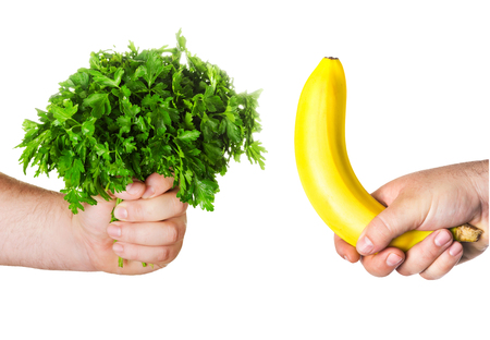 man\'s hand holding a large bunch of parsley, fresh herbs, the other man\'s hand holding a bananaの写真素材