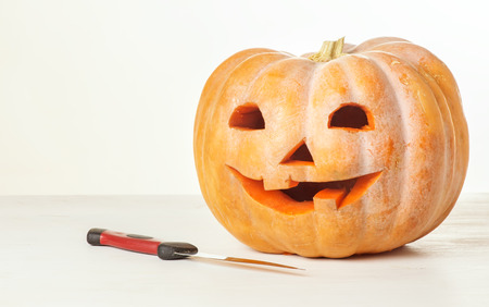 Cut the pumpkin for Halloween, a knife and carved pumpkin on the tableの写真素材