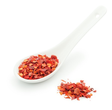 Dried chopped red hot chili pepper in a ceramic spoon isolated on a white background closeupの写真素材