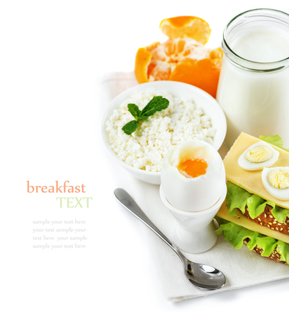 Delicious healthy breakfast of fresh products, yogurt, cottage cheese, boiled egg in the stand, sandwiches with cheese, tangerines, composition on a white background, space for texの写真素材