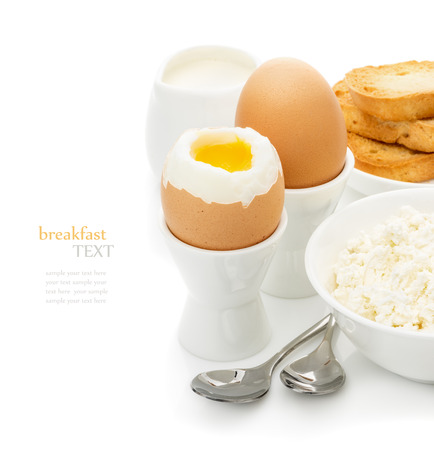 Healthy delicious breakfast, soft boiled eggs in the stands, toast with cheese, cottage cheese,  cream on a white background, the concept of protein foodの写真素材