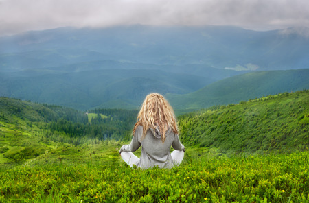 A young blond Caucasian woman meditating in the Carpathian mountainsの写真素材