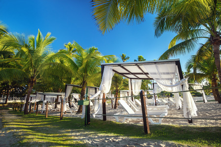 beach with sun loungers and gazebo in Juan Dolio in the Caribbean, tropical landscape, palm trees, sea, blue sky, Dominican Republicの写真素材