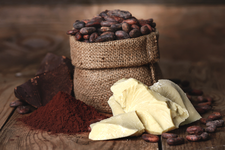 Cocoa butter and ingredients for making chocolate, Cocoa powder in the bowl, cocoa beans on old wooden background