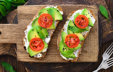 Bright vegan avocado sandwiches on a wooden cutting boardの写真素材