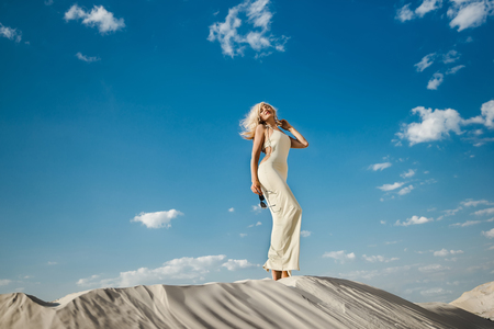 Beautiful caucasian blond woman in the desert in a sexy dressの写真素材