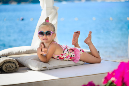 Little Caucasian charming three years old girl lies and tansの写真素材