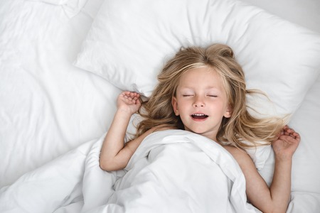 little child girl sleeping in the bedの写真素材