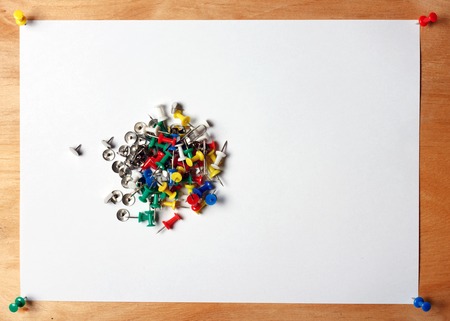 Paper and many color thumbtacks red, blue, green, yellow, white . A sheet of paper attached to a wooden board officeの写真素材
