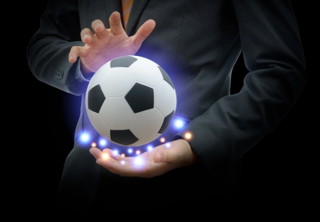 Businessman holding football isolated on blackの写真素材