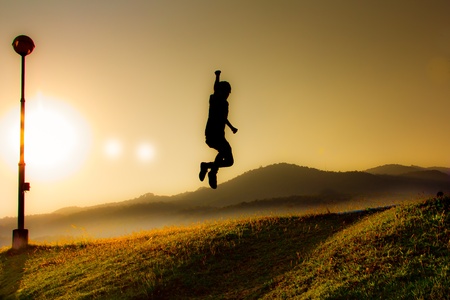 Silhouette of a jumping man on the skyの写真素材