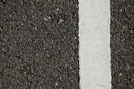 Texture closeup of an asphalt road with painted white line on the sideの写真素材