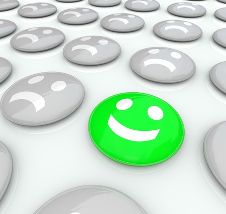 One face smiles among a collection of many frowning faces, symbolizing uniqueness and positive attitude to make you stand out from the crowd and be differentの写真素材