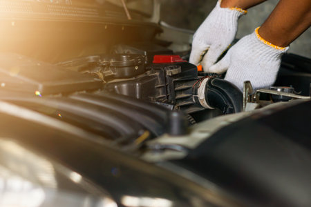 The hands of a man wearing gloves repairing a car engine in a garageの写真素材
