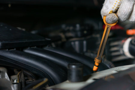 A man wearing gloves checks the oil in a car engineの写真素材