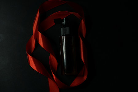 Red satin ribbon around the bottle on a black backgroundの写真素材