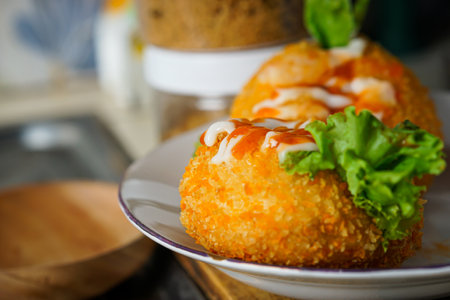 close-up photo Fried patties filled with lettuce and sausage topped with hot sauce and mayonnaise, served on a white plate with a jar on the side. selective focusの写真素材