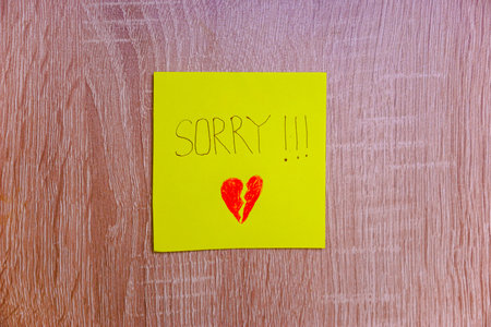 A heartfelt note on a yellow sticky note expresses deep remorse with a broken heart drawing.の写真素材