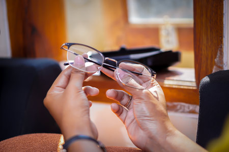 A close-up of hands delicately holding a pair of glasses, showcasing craftsmanship and attention to detail.の写真素材