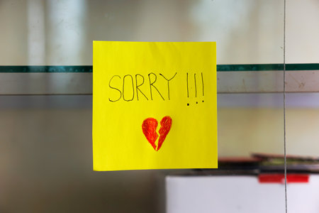 A heartfelt note on a yellow sticky note expresses deep remorse with a broken heart drawing.の写真素材