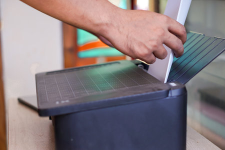 A person feeds blank paper into the printer