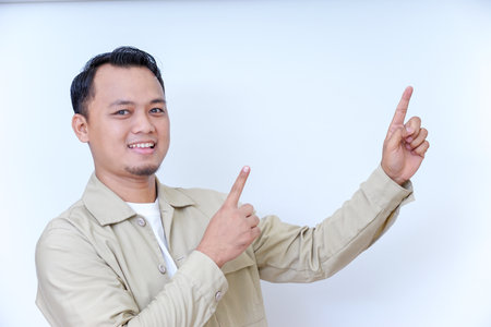 A smiling man in a beige jacket gestures with his hand, pointing at something.の写真素材