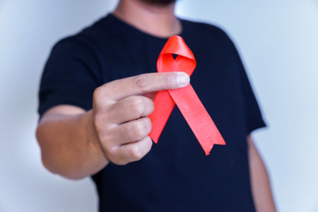 A person holding a red ribbon, symbolizing awareness and support for health issues.