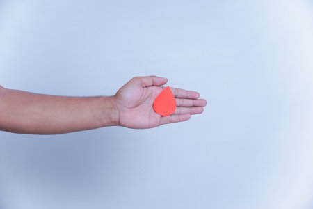 a hand hold a drop of donor blood with white background. world blood donor day concept,の写真素材