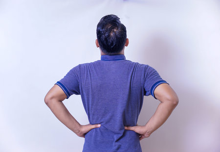 back view of An man stands with hands on hips, showing confidence and contemplation.