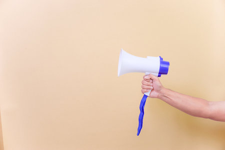 a hand hold megaphone speaker isolated on beige backgroundの写真素材