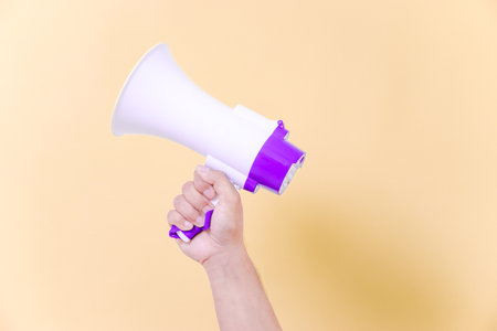 a hand hold megaphone speaker isolated on beige backgroundの写真素材