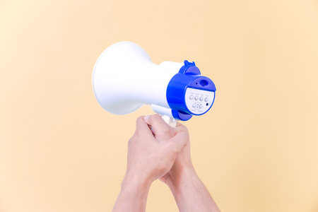 a hand hold megaphone speaker isolated on beige backgroundの写真素材
