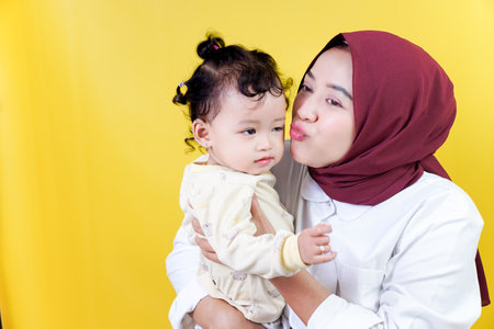 A joyful asian mother interacts with her happy child against a bright yellow background mothers day conceptの写真素材