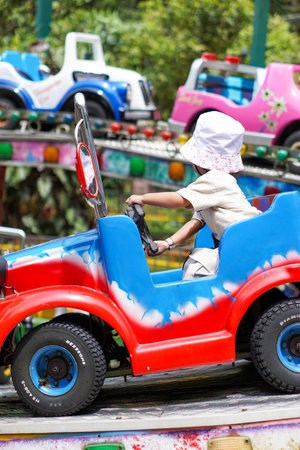 Child driving a colorful car on a carnival ride.の写真素材