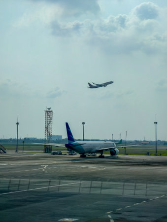 Airport scene with parked and taking off airplanes.
