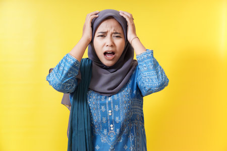 Stressed woman in hijab with hands on head.
