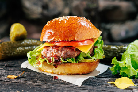 Cheeseburger with pickled cucumbers on rustic wooden tableの写真素材