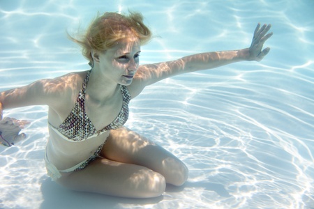 Girl swimming underwater in a swimming pool の写真素材