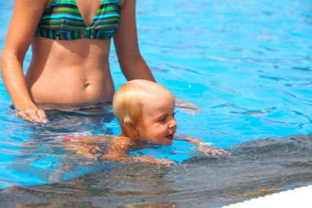 Child having fun in water with mom の写真素材