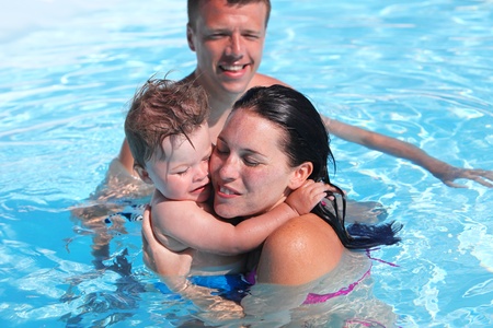 Photo of happy family of parents and cute son in swimming poolの写真素材