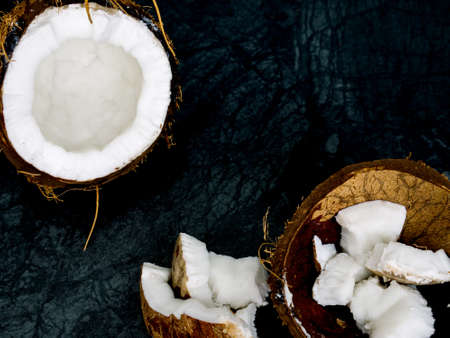Coconut pieces broken isolated on dark background as package design elementの写真素材