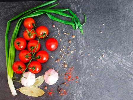 Fresh cherry tomatoes on black background with onion and garlic. Top view with copy space.の写真素材