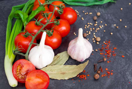 Fresh cherry tomatoes on black background with onion and garlic. Top view with copy space.の写真素材