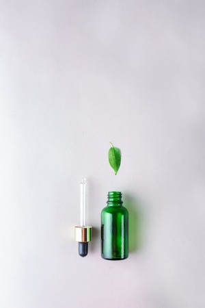 The minimal style. Natural skin care, cosmetics. Eco. Green glass bottle with a pipette in pastel colors. Flat lay.の写真素材