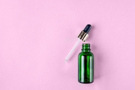 Minimalist photo of skin care, packaging for cosmetics. Green glass bottle with a pipette in pastel colors. Flat lay.の写真素材