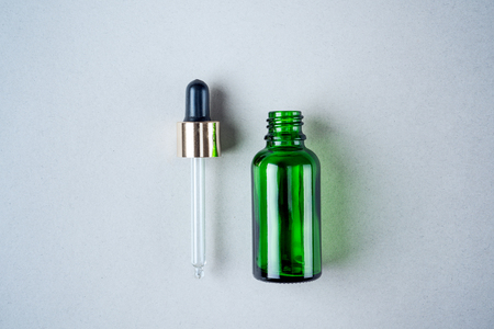 Minimalist photo of skin care, packaging for cosmetics. Green glass bottle with a pipette in pastel colors. Flat lay.の写真素材